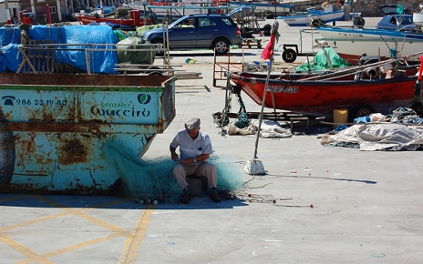 A fisherman fixes his net in Baiona